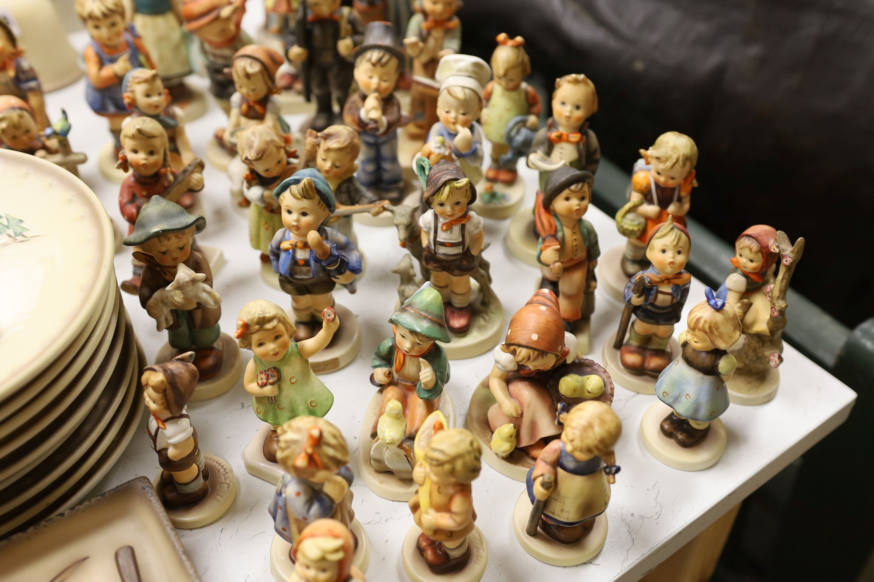 A large collection of Hummel pottery figures, approximately 70 including skier and two similar plaques, some with boxes.